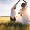 A couple dancing in grass against the sun