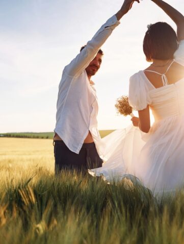 A couple dancing in grass against the sun